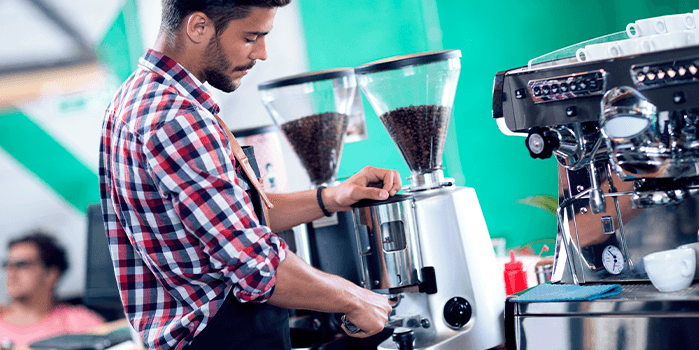 Homem faz moagem e torra do grão em microtorrefadora de café