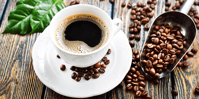 Xícara de café cercada de grãos; vivemos a terceira onda do café atualmente