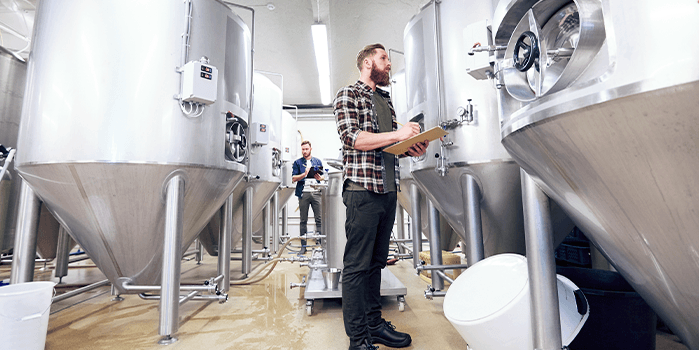 Homem circula pela estrutura da cervejaria para checar produção